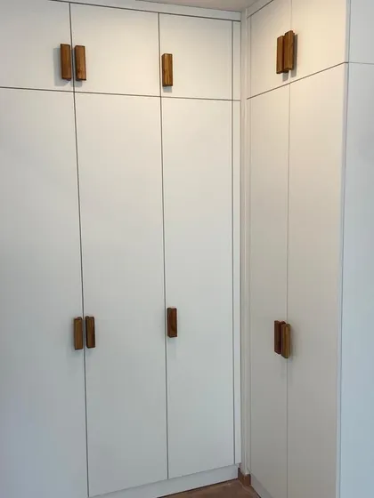Inspired by clean Scandinavian design, this wardrobe combines matte white acrylic shutters with custom-made natural wood veneer handles. The result is a minimalist and highly functional storage solution that feels both modern and warm.