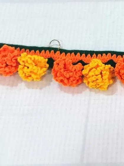 This marigold toran is designed for easy hanging with built-in rings. The dense arrangement of orange and yellow flowers creates a vibrant and welcoming look for your main door during festivals.