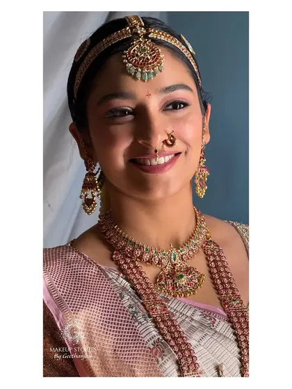 A smiling portrait of Mithila on her wedding day. The soft pink tones in her makeup perfectly complement her beautiful pastel saree.