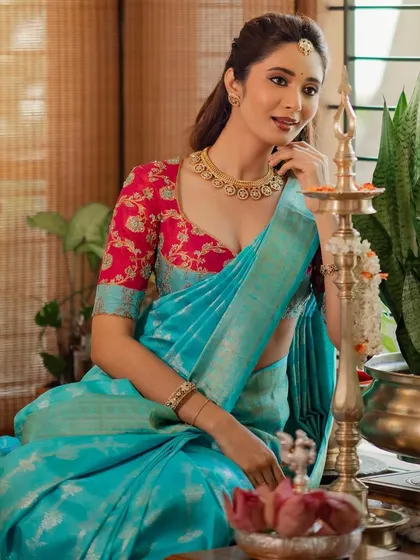 A festive look featuring a sky blue Kanchivaram saree paired with a contrasting pink blouse with floral embroidery. This combination is perfect for celebrations like Diwali.