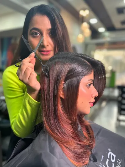 Our stylist, shears in hand, ready to perfect this sharp cut with its beautiful red ombre. This shot shows our vision and precision.