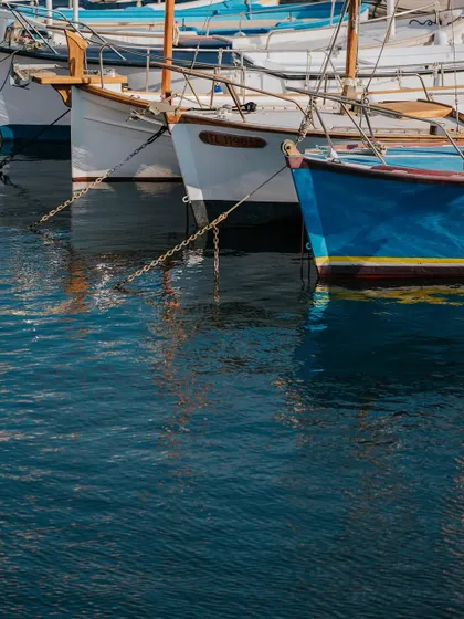 Reflections of traditional fishing boats in the calm harbor water of St. Tropez. This composition plays with color, reflection, and texture to create a visually interesting image.