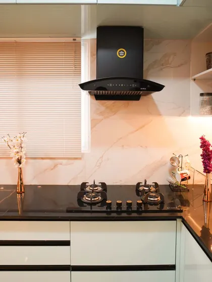 This close-up highlights the details of a modern kitchen, including a five-burner hob set into a black granite countertop. The marble-style backsplash and warm under-cabinet lighting create an inviting and functional cooking area.