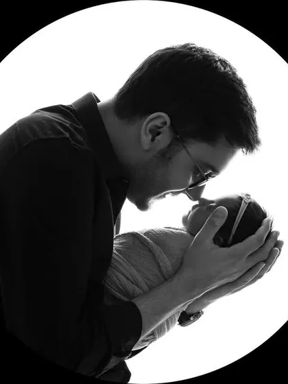A father's gentle love for his newborn twin, captured in a striking black and white silhouette. It's a powerful image of the paternal bond.