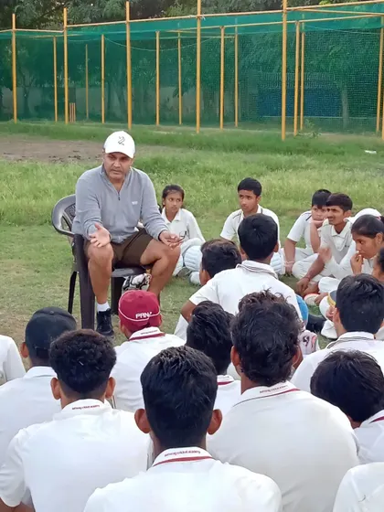 A focused moment as trainees listen to advice from Virender Sehwag, with our practice nets visible in the background.