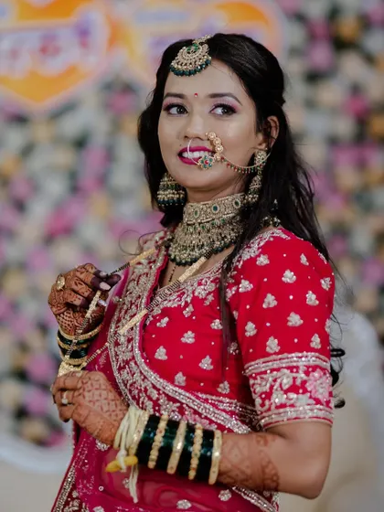 A candid shot of our happy bride. Her makeup features a subtle pink and gold eye look that complements the red of her outfit, and the traditional nath completes her look.