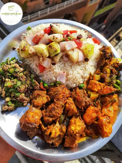 A feast for meat lovers. This thali includes chicken curry, fish curry, a spicy liver chutney, and a stir-fried fish head, served with rice and salad.