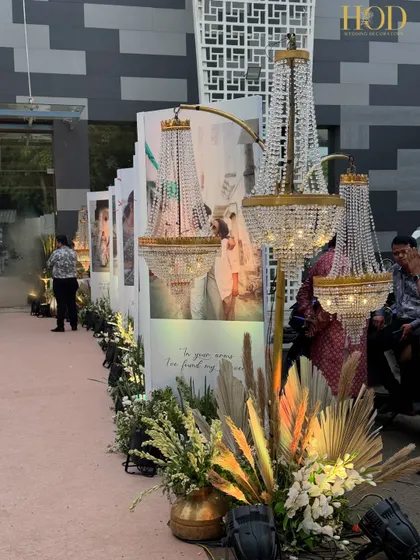 The combination of personal photos and grand chandeliers creates a unique entrance that is both intimate and luxurious. The warm lighting and pampas grass arrangements add to the romantic atmosphere.