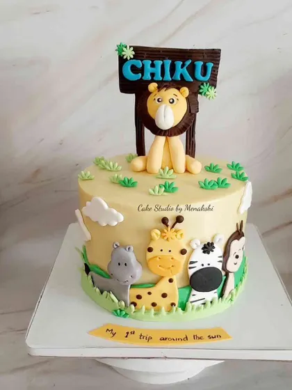 A cute jungle themed first birthday cake for Chiku's 'first trip around the sun'. The cake features a friendly lion, hippo, giraffe, and zebra.