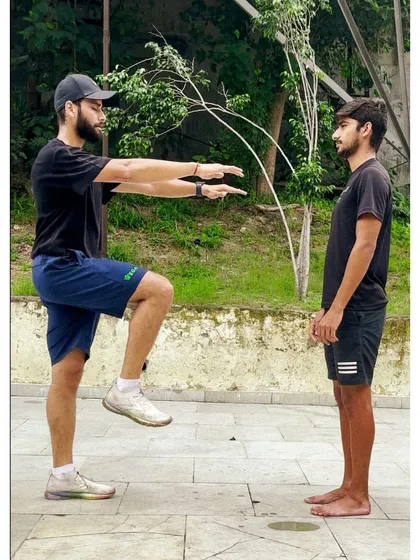Demonstrating a movement to an athlete. Visual cues are a powerful coaching tool, helping to ensure the athlete understands the correct form and technique.