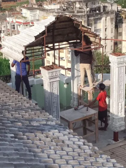 The beginning stages of the custom terrace mandir, showing the structural framework and the first stone pieces being lifted into place.