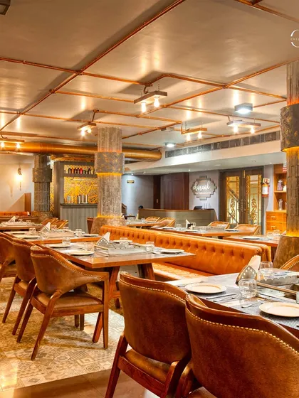 The dining area is characterized by a mix of patterned floor tiles and warm wooden furniture. The lighting is kept low and warm, using industrial-style fixtures to enhance the cozy, traditional-meets-modern vibe.