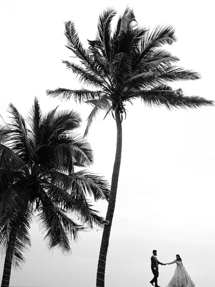A dramatic black and white silhouette against the vastness of the sea and sky. This style of photography strips away color to focus on the form, connection, and emotion between the couple.