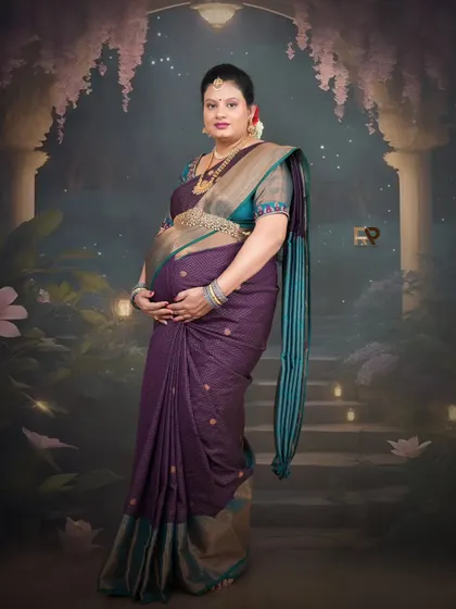 A full-length portrait in a beautiful purple saree. The backdrop, with its soft lighting and grand staircase, creates a magical, palace-like atmosphere.