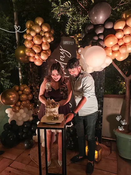 The cake cutting moment is always special. Here, the couple celebrates in front of the bold black, white, and gold birthday backdrop we created for an unforgettable night.