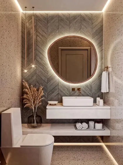 This bathroom design combines textured walls with modern fixtures for a spa-like feel. Key features include a floating vanity with a vessel sink, an organically shaped backlit mirror, and layered ambient lighting to create a warm and inviting retreat.