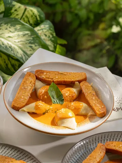 Stuffed conchiglie pasta shells in a creamy tomato sauce. The lighting highlights the texture of the sauce.