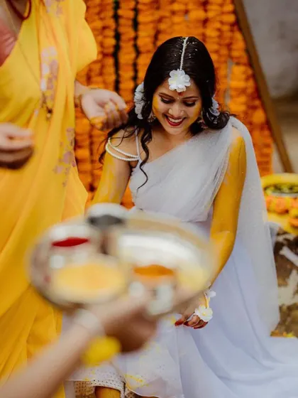 The bride smiles as the Haldi rituals begin. The traditional marigold flower decor is a key element of our Haldi decoration packages.
