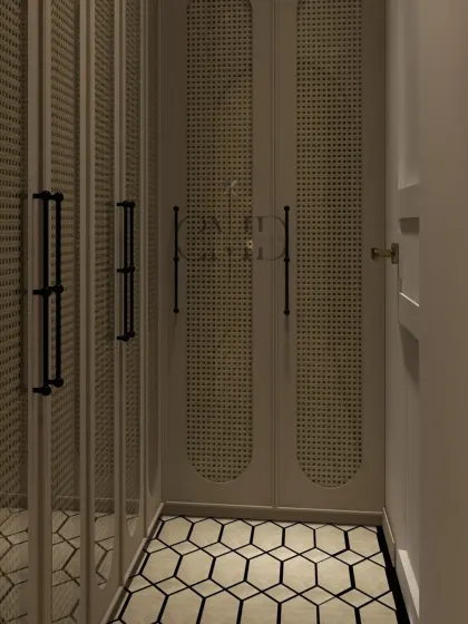 The narrow passage of the walk-in wardrobe is lined with full-height cane-paneled closets, maximizing storage while maintaining a sophisticated look.