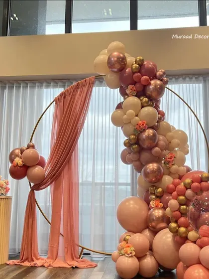 A beautiful circular frame decorated with a balloon garland and a flowing pink drape. The color palette of dusty rose, blush, and rose gold is very elegant and works well for bridal showers, engagements, or milestone birthdays.