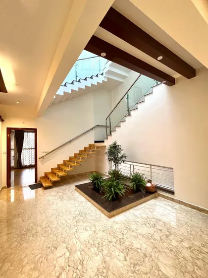 In Mr. Vinay's residence, the staircase is designed as a floating structure above a small indoor garden. This placement integrates the staircase into the home's central courtyard theme, blending architecture with nature.