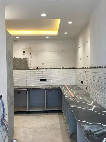 This is the beginning of a kitchen transformation. The basic structure and countertop are in place, with the walls tiled and ready for the modular cabinets to be installed.
