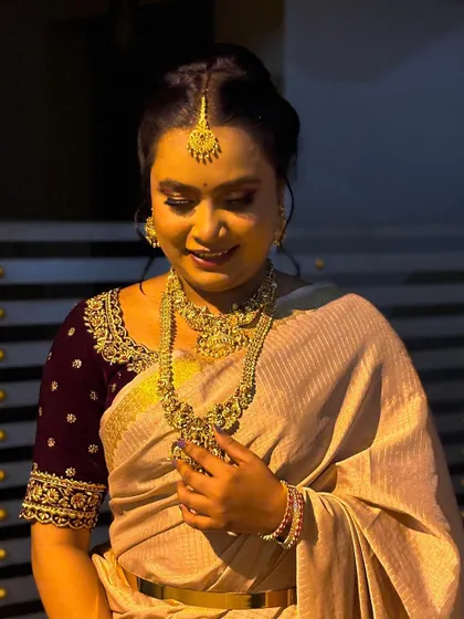 A candid moment from a photoshoot. The soft lighting highlights the dewy finish on the skin and the intricate temple jewellery.