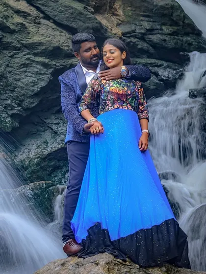 An example of our outfits in a natural setting, this couple is posed against a waterfall. The man's patterned blue blazer perfectly complements the woman's vibrant blue gown with its floral bodice.