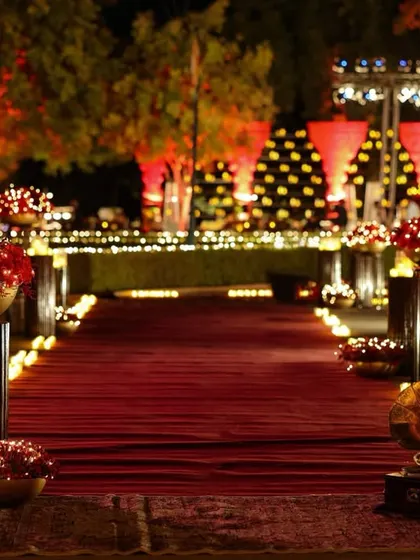 The grand entrance path, lined with candles and stands holding bowls of red roses, leading towards the majestically lit Umaid Bhawan Palace.