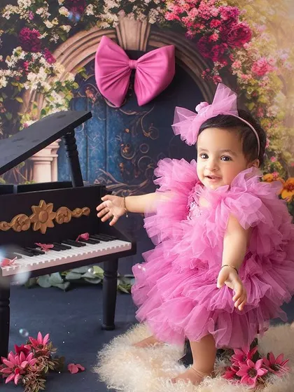 Miss "Onederful" at her piano. A creative and whimsical first birthday shoot with a floral backdrop and bubble accents.