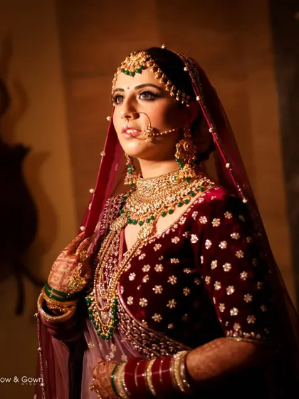 A stunning bridal portrait. The warm, golden light illuminates her beautiful velvet lehenga and intricate jewellery, capturing her looking regal and serene.