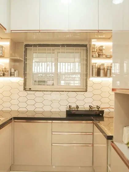 A view into a U-shaped kitchen from the living area, showcasing how our designs create a seamless flow between spaces. The kitchen features white cabinets, a hexagonal backsplash, and warm lighting.