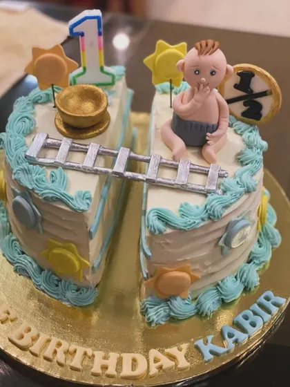 A creative half-birthday cake for Kabir. The cake is split in two, connected by a ladder, with a baby figure celebrating the six-month milestone.