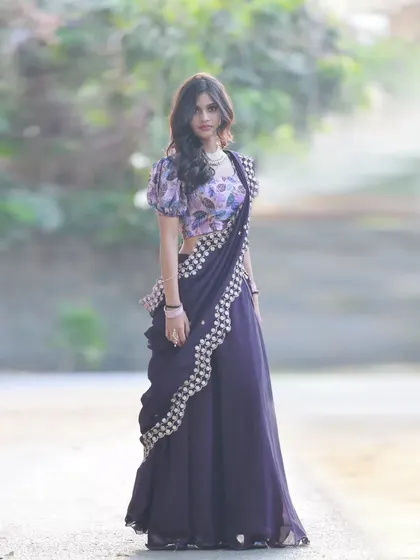 A full-length shot of a different half-saree from the same collaboration. This one features a dark purple skirt and a floral-printed blouse, showing a different style.
