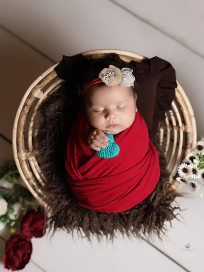 A simple and sweet moment, with the newborn holding a small heart prop. The focus is on the baby's tiny hands and peaceful expression.