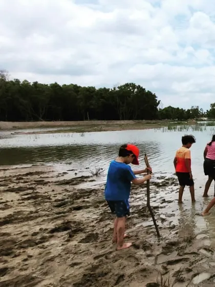 With sticks in hand, children explore the muddy lake shore, fully immersed in their environment.