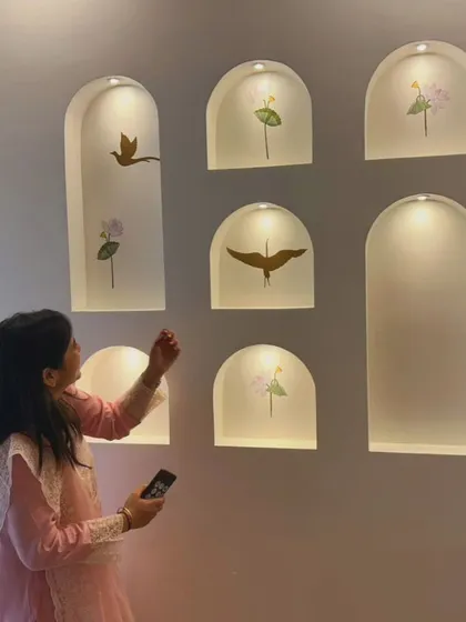 A candid moment of our client admiring the newly finished accent wall in her home. The illuminated niches with bird and flower decals have become her favorite corner.
