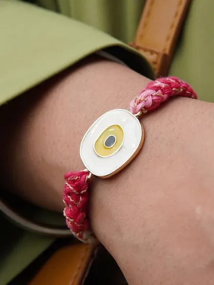The yellow Evil Eye Rakhi worn on the wrist. It's perfect for sisters too!