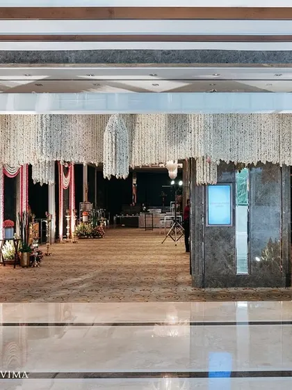 The entrance to a half-saree ceremony, adorned with fragrant jasmine garlands and banana leaves. The reflection on the polished floor doubles the beauty of this traditional South Indian decor.