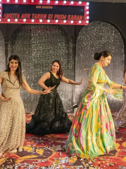 The bride squad takes the stage for their sangeet performance, in front of a glittering silver backdrop.