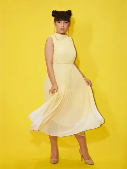 A full-length view of the playful and chic look from our Summer Edit. The flowing yellow dress and modern hairstyle create a fresh and fashionable statement.