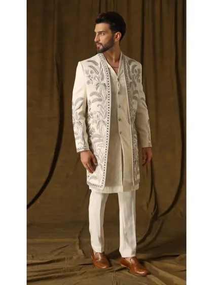 This ivory Indo-Western shrug set, named 'Pragyan', features a long, open-front jacket with dense, garden-inspired embroidery. Paired with a handwoven geometric-patterned kurta and cigarette trousers, it exemplifies my layered, fusion-forward approach.