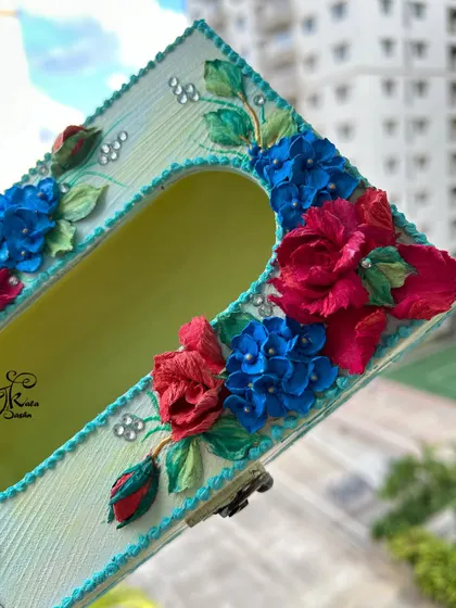 I love combining bold colors, like the bright red roses and deep blue hydrangeas on this tissue box. It creates a striking contrast that is very eye-catching.