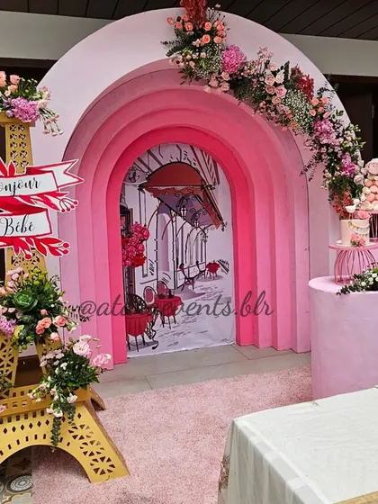 A chic and elegant Paris-themed baby shower. The decor features a stunning backdrop of pink arches, a miniature Eiffel Tower, and a beautifully set table, transporting guests to the city of love.