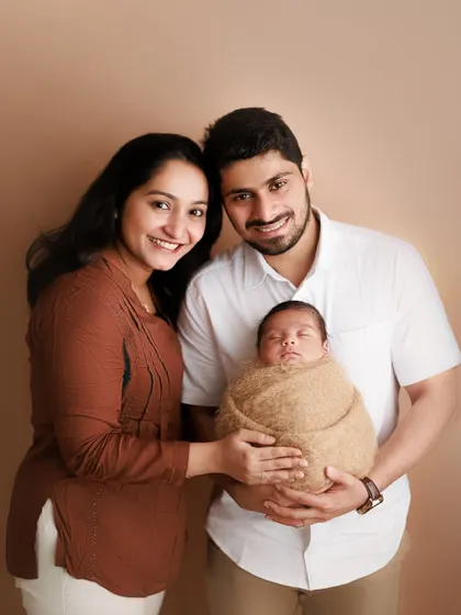 The sweetness of a new family. This classic studio portrait captures the proud smiles of the new parents as they hold their precious, sleeping baby.