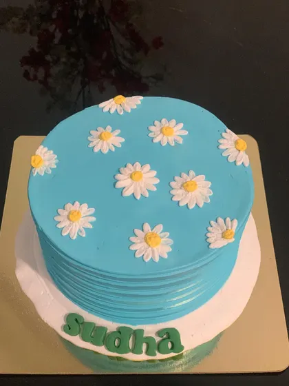 A simple and elegant daisy cake. The light blue cake is decorated with hand-piped white and yellow daisies for a fresh, cheerful look.