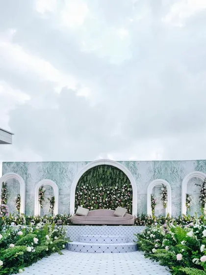 For the modern couple, we craft chic and sophisticated backdrops that speak to their style. This reception stage features a clean, marble-effect wall with integrated floral arches, creating a look of timeless elegance and contemporary design.
