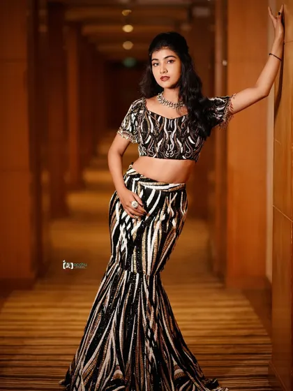 A full-length shot that uses the long corridor to create a sense of depth and drama. The pose is strong and fashionable, perfect for a modern ethnic wear lookbook.