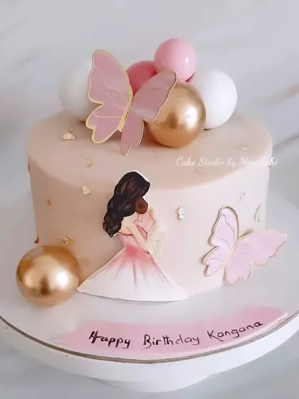 A lovely cake for a new mother, decorated with a mother and baby illustration, pink butterflies, and pink and gold spheres. A sweet way to celebrate a new chapter.