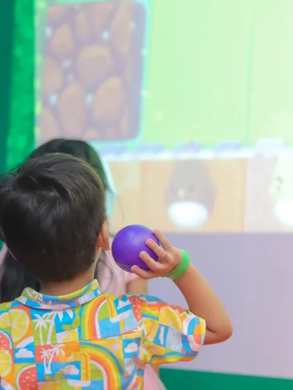 A young gamer takes aim at the interactive screen. This activity is excellent for improving hand-eye coordination while being incredibly fun.